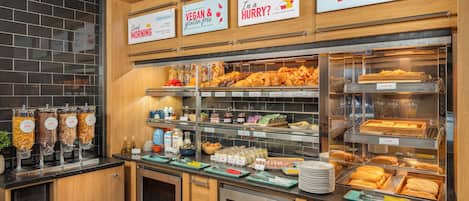Un bufé de desayuno con diversas opciones de alimentos y señalización clara que indica alternativas veganas y sin gluten.