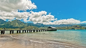 A pier extending into a clear blue sea with mountains in the background. - Hanalei Bay Resort 9221 & 9222 By Parrish Kauai (Princeville)