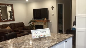 A kitchen with a granite countertop, white cabinets, and a welcome sign.