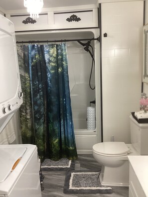 Un baño con ducha, inodoro y una bañera blanca.