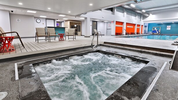 Un vestíbulo de hotel con una amplia piscina interior, zona de estar y un mostrador de recepción.