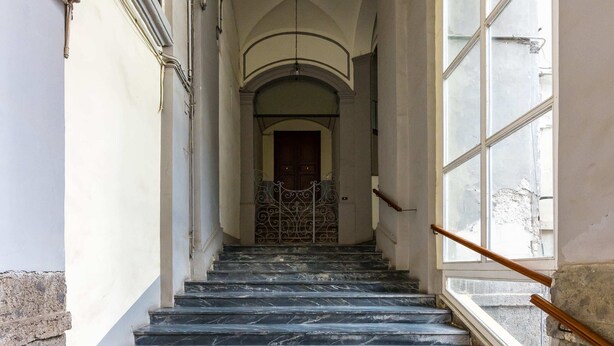Eine Marmortreppe führt zu einem Raum mit einem großen Fenster und einer Tür.