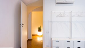 Ein Flur mit einem weißen Schrank, einer Kleiderstange und einem Blumentopf.