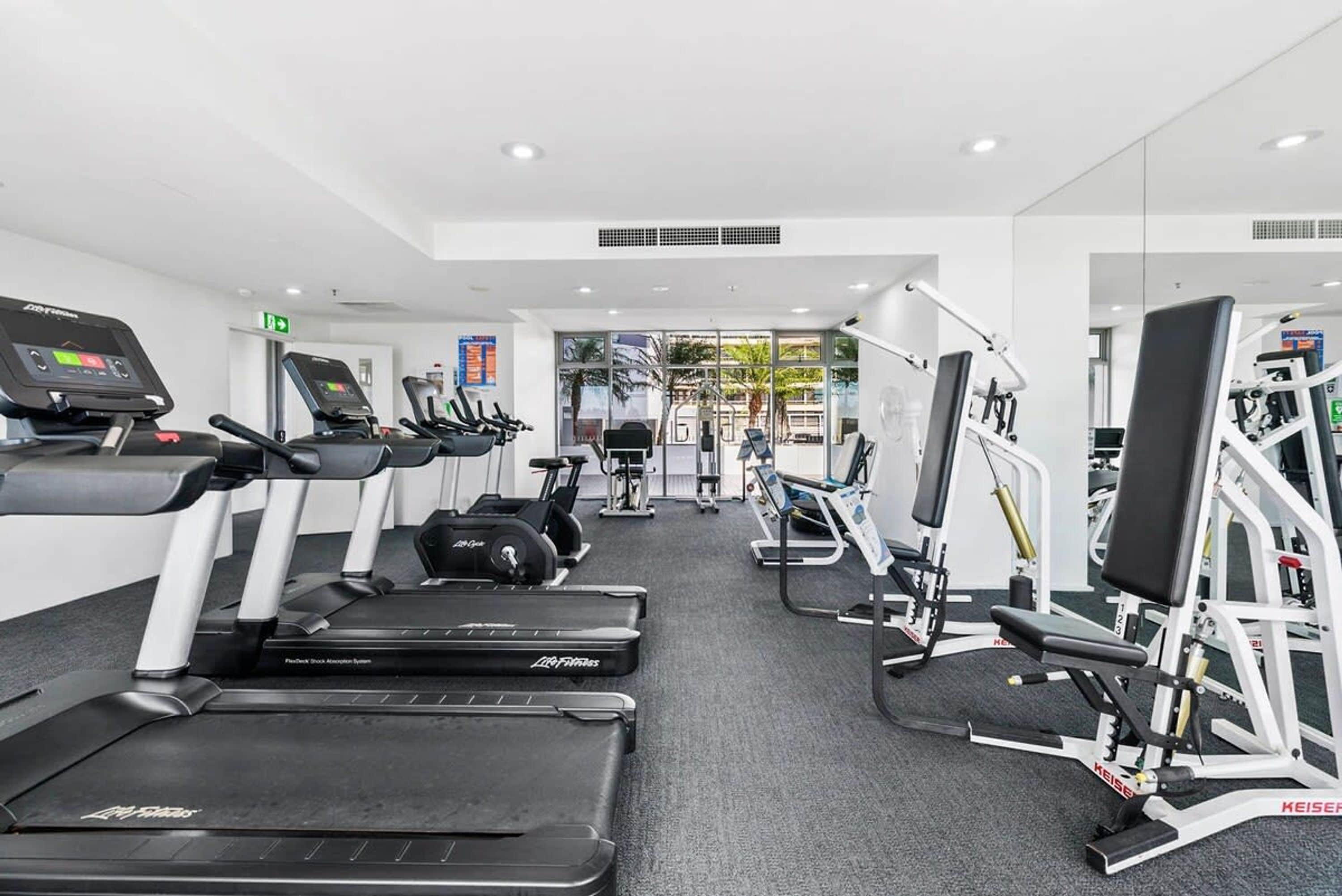 Un gimnasio moderno con cintas de correr, elípticas y máquinas de pesas.