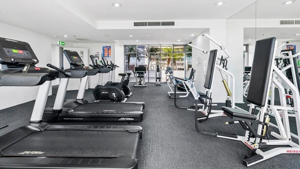Un gimnasio moderno con cintas de correr, elípticas y máquinas de pesas.