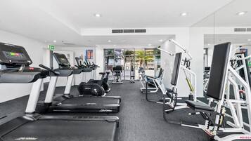 Un gimnasio moderno con cintas de correr, elípticas y máquinas de pesas.