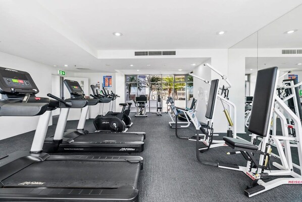 Een moderne sportschool met loopbanden, elliptische trainers en krachttoestellen.