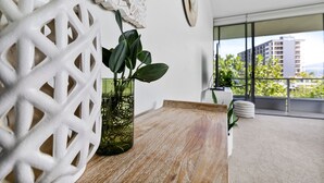 Een moderne woonkamer met een houten tafel, een decoratief wit wandobject en een potplant.