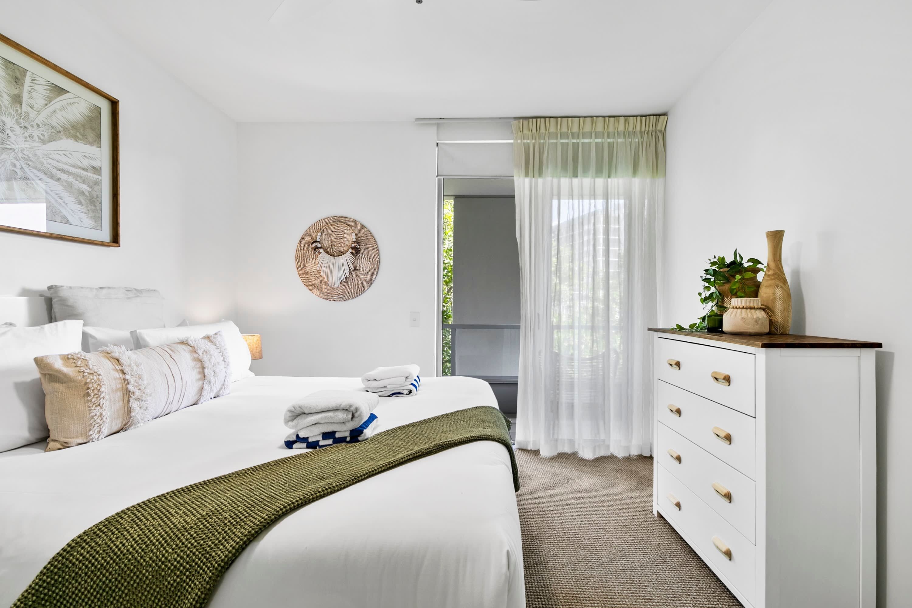 A neatly arranged bedroom with a bed, bedside table, and a dresser.