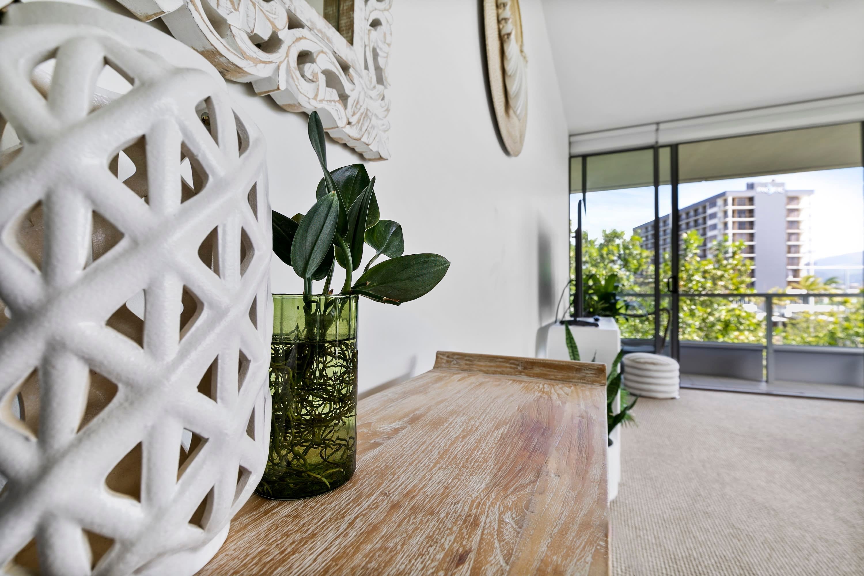A modern living room with a wooden table, a decorative white wall piece, and a potted plant.