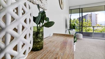 A modern living room with a wooden table, a decorative white wall piece, and a potted plant.