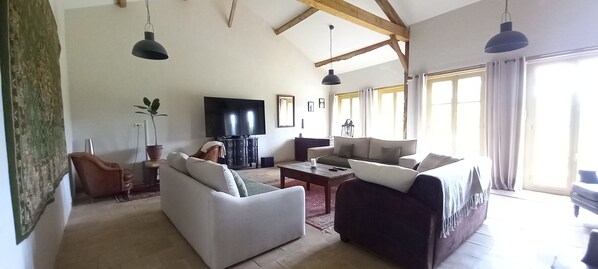 A living room with a sofa, armchairs, a coffee table, a TV, and a fireplace.