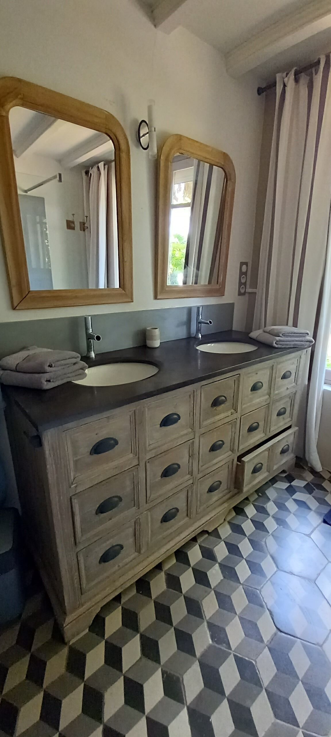A bathroom with a wooden vanity, two mirrors, a sink, and a patterned floor.