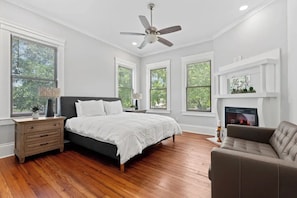 A bedroom with a bed, a nightstand, a dresser, a fireplace, and a ceiling fan. - Luxury Casa B
(Savannah)