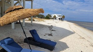 A beach with lounge chairs and a thatched umbrella. - Private Beachfront w/ Sauna, Hottub, Golf Cart, Kayaks, Paddle Boards & Bikes + (Alligator Point)