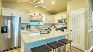 A modern kitchen with a central island, stainless steel appliances, and a ceiling fan. - Private Beachfront w/ Sauna, Hottub, Golf Cart, Kayaks, Paddle Boards & Bikes + (Alligator Point)