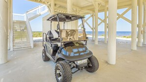 A golf cart parked under a covered area with a beach view. - Private Beachfront w/ Sauna, Hottub, Golf Cart, Kayaks, Paddle Boards & Bikes + (Alligator Point)