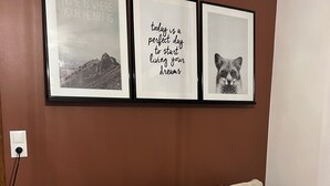A living room with a beige sofa, three framed motivational quotes, and a power outlet on the wall.