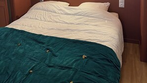 A bedroom with a bed, teal and white bedding, and two wall-mounted light fixtures.
