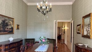 Une salle à manger élégante, avec une longue table en bois, des chaises, un lustre et des œuvres d’art encadrées accrochées aux murs.