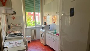 Une cuisine compacte équipée d’un lave-linge, d’un four à micro-ondes et d’un réfrigérateur.