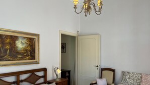 Une chambre à coucher comprenant un lit, une chaise, un bureau, un tableau et un lustre.