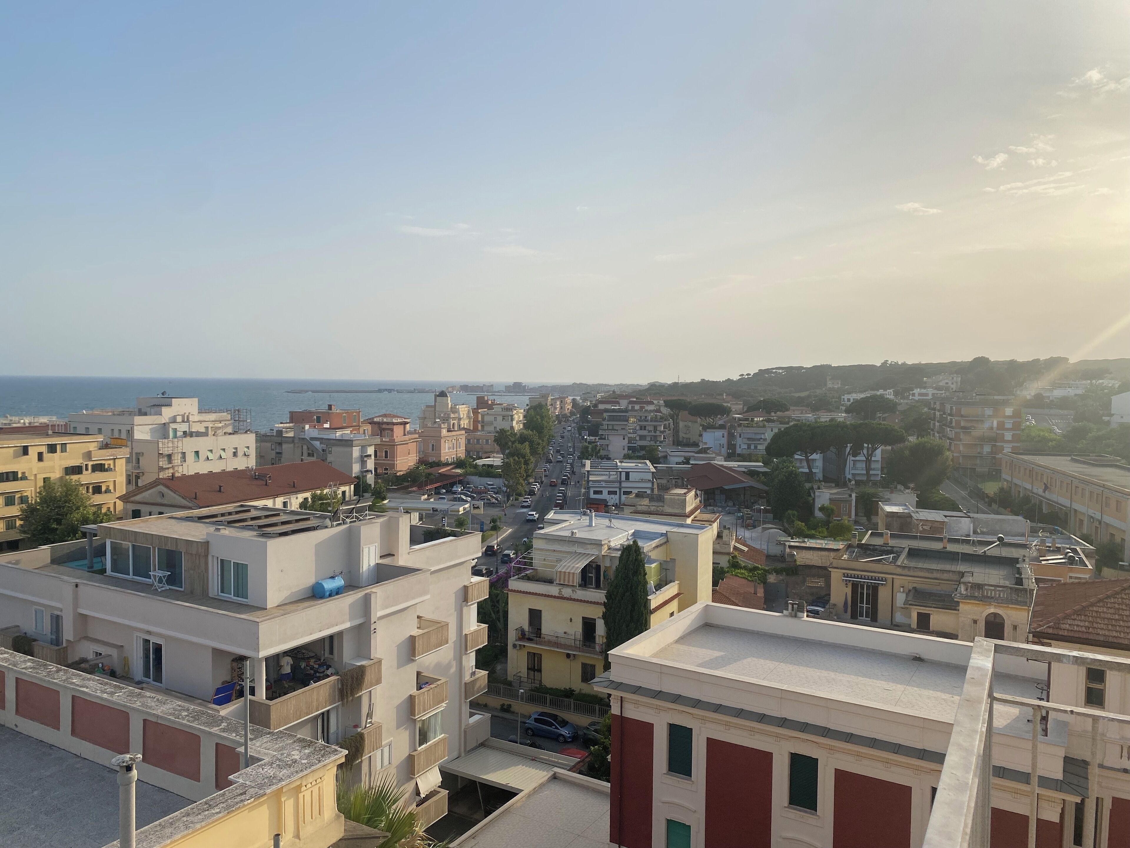 Paisagem costeira com edifícios modernos e tradicionais, céu claro e vista para o mar.