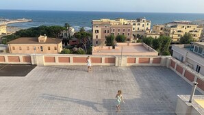 A rooftop terrace with a view of the sea and buildings. - Casa Nettuno (Nettuno)