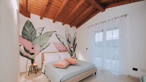 A bedroom with a bed, a nightstand, a large plant, and a window with sheer curtains. - Memi's Home - Family villa whit big exclusive garden, 7 km from Salò, Garda Lake (San Biagio)