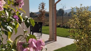 A covered patio area with a table and chairs, surrounded by greenery and a view of the countryside. - Memi's Home - Family villa whit big exclusive garden, 7 km from Salò, Garda Lake (San Biagio)
