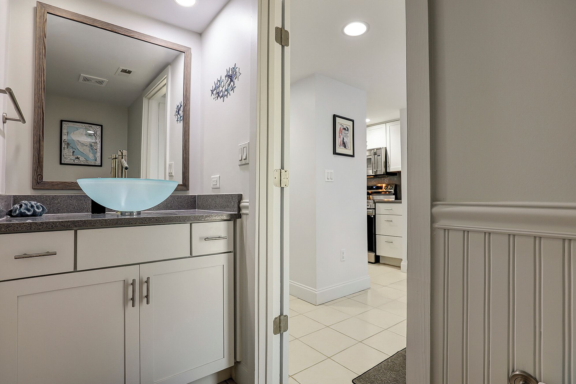 A modern bathroom with a large mirror, a blue sink, and white cabinetry.