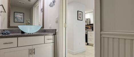 A modern bathroom with a large mirror, a blue sink, and white cabinetry.