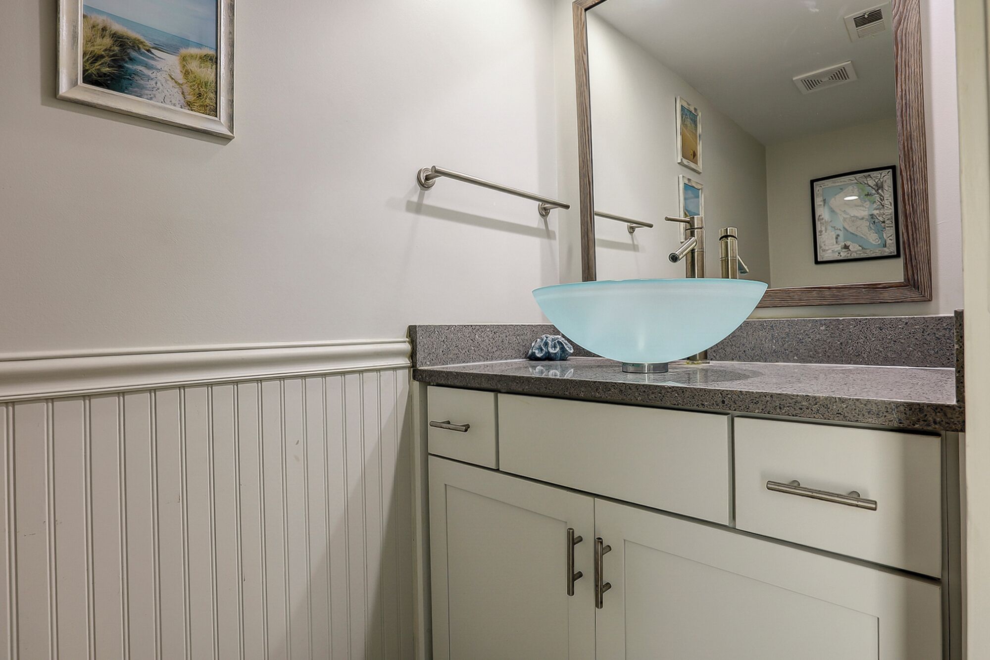 A bathroom with a white vanity, a glass bowl sink, and a mirror above the sink.