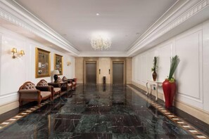 A hotel lobby with a marble floor, seating area, wall-mounted lamps, and a chandelier. - New Kwangsi Style Hotel (Guilin)
