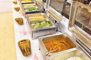 Un buffet proposant une variété de plats présentés dans des récipients en métal.