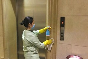 A person cleaning an elevator interior. - New Kwangsi Style Hotel (Guilin)