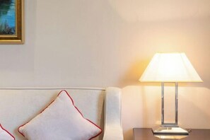 A room with a white sofa, a lamp on a side table, and a framed picture on the wall. - New Kwangsi Style Hotel (Guilin)