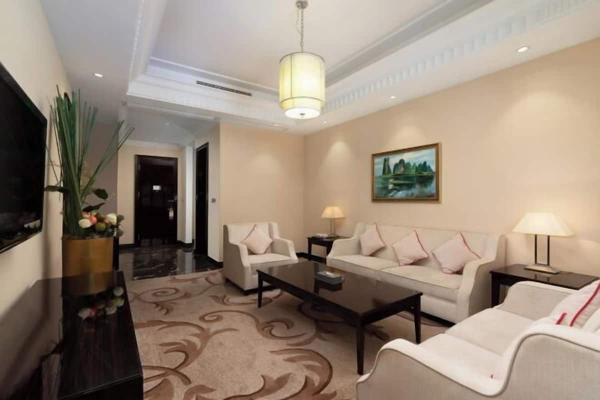 A hotel lobby with a sofa set, a coffee table, a TV, and a painting on the wall.