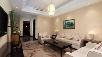 Un hall d’hôtel avec un ensemble de canapés, une table basse, un téléviseur et un tableau accroché au mur.