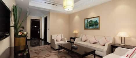 Un hall de hotel con un conjunto de sofás, una mesa de centro, un televisor y un cuadro en la pared.