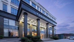 A modern hotel with a prominent entrance, large windows, and a clear sky.