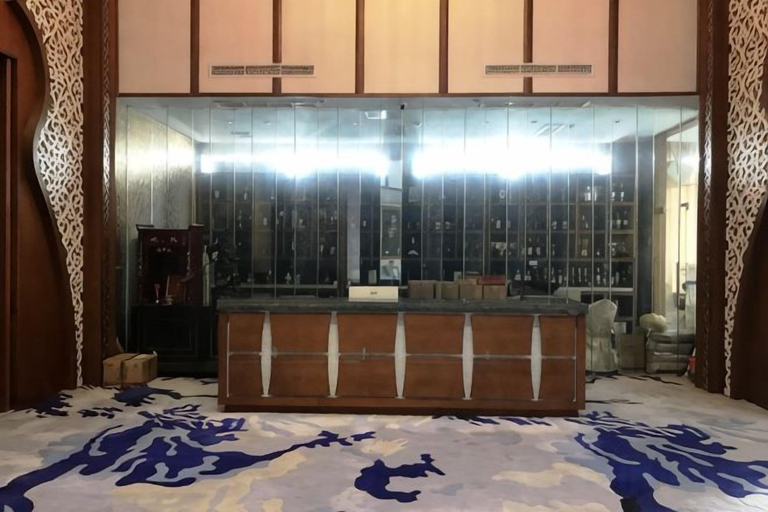 A reception area with a counter, a mirror, and a patterned carpet.