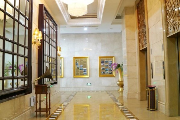 A hotel lobby with a marble floor, a grand piano, framed pictures on the wall, and a reception desk. - New Kwangsi Style Hotel (Guilin)