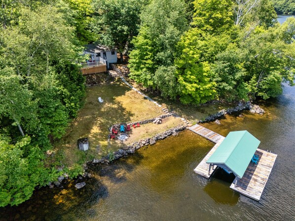 A lakeside cabin with a dock, surrounded by dense forest.