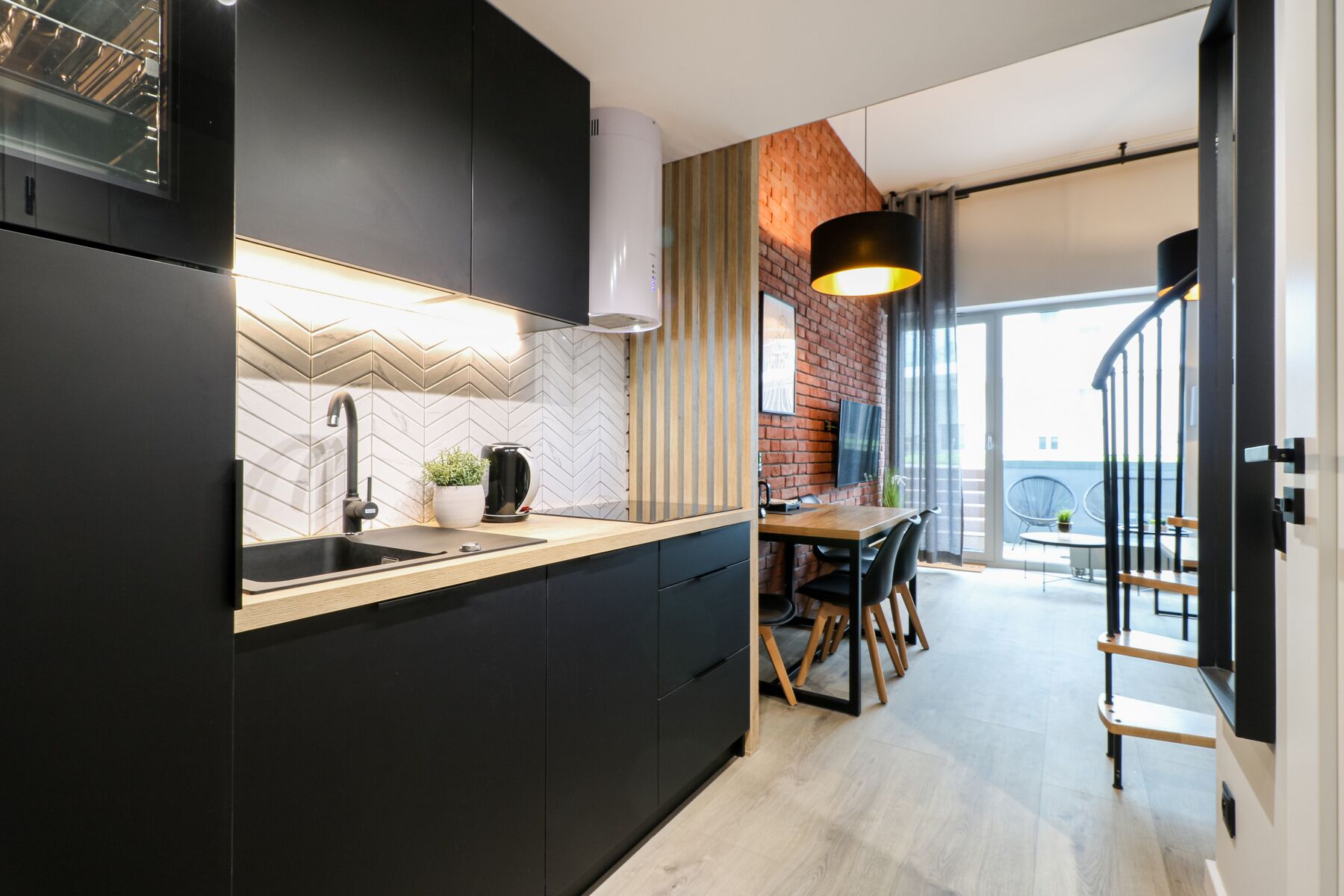 A modern kitchen with a herringbone tile backsplash, a black countertop, and a built-in oven.
