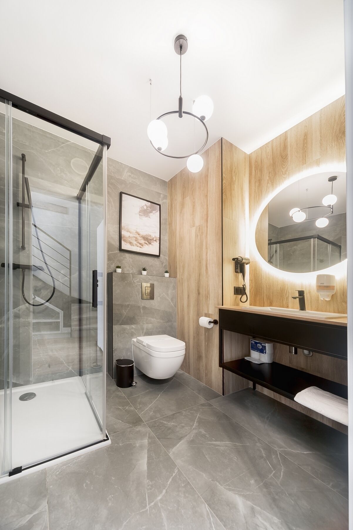 A modern bathroom with a glass shower enclosure, a wooden vanity, and a large mirror.