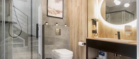 A modern bathroom with a glass shower enclosure, a wooden vanity, and a large mirror.