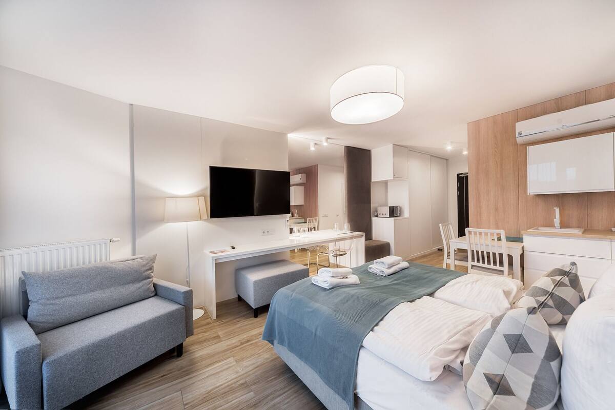 Ein modernes Hotelzimmer mit Bett, Sofa, Schreibtisch und Fernseher.