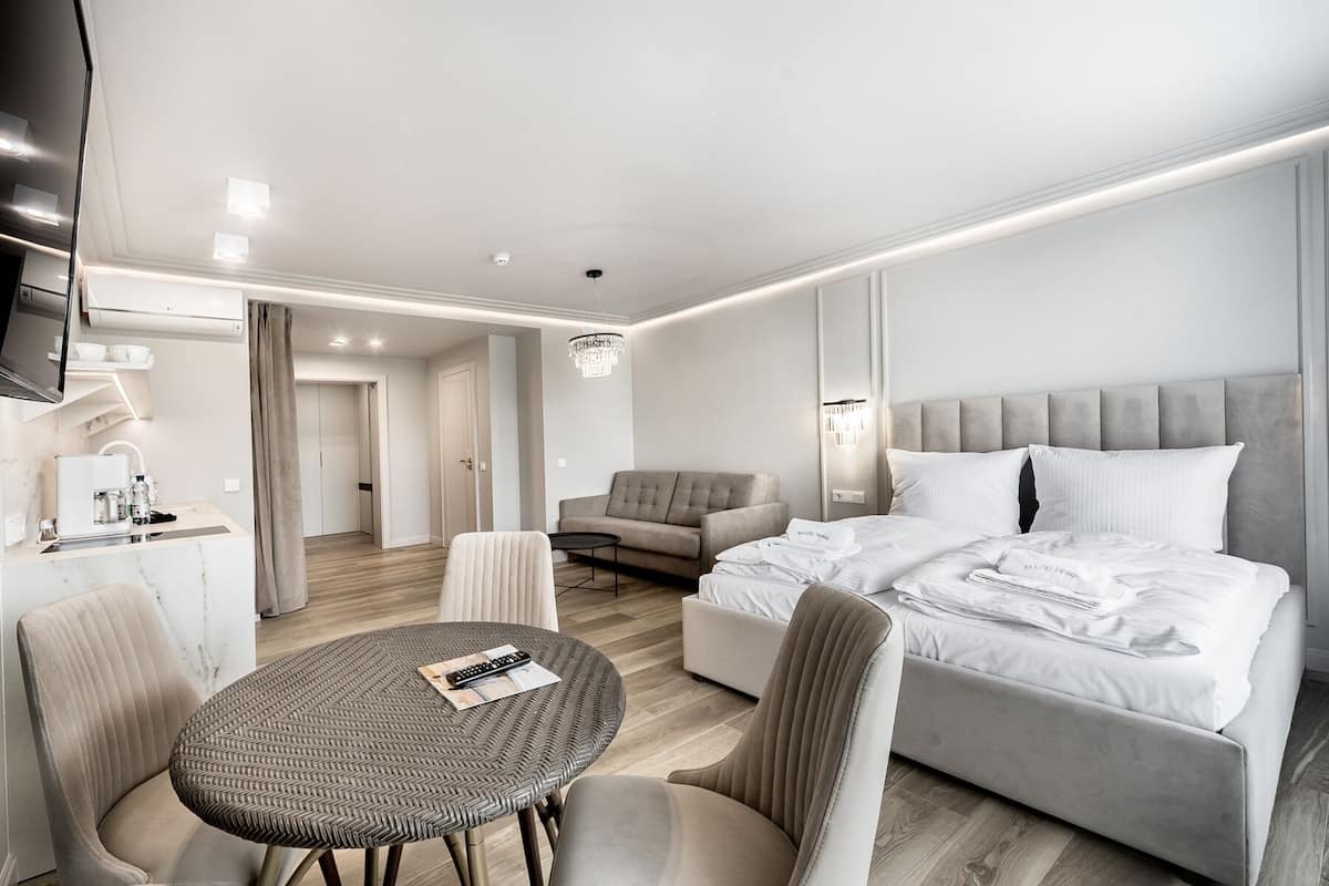 Ein modernes Hotelzimmer mit einem Bett, einer Couch, einem Esstisch und einem Fernseher.