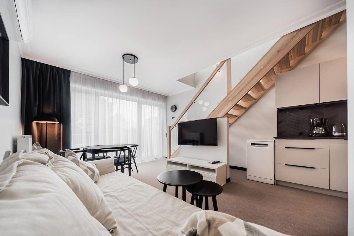Eine moderne Wohnung mit Wohnzimmer, Essbereich, Küche und einer Treppe.